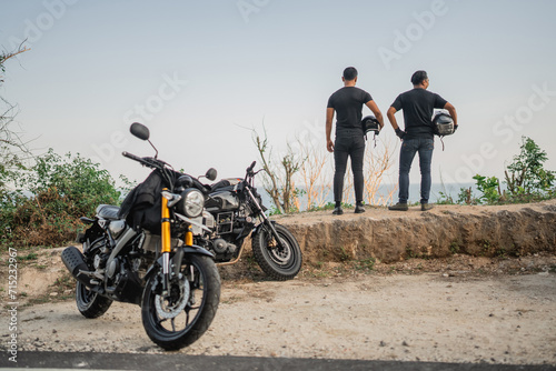 asian riders holding helmet and standing on cliff