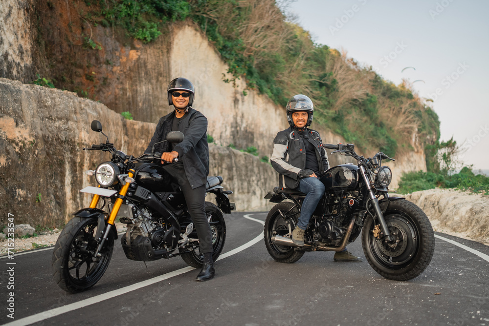 indonesian men wearing jacket and helmet sitting on motorbike on the road indonesian men wearing jacket and helmet sitting on motorbike on the road