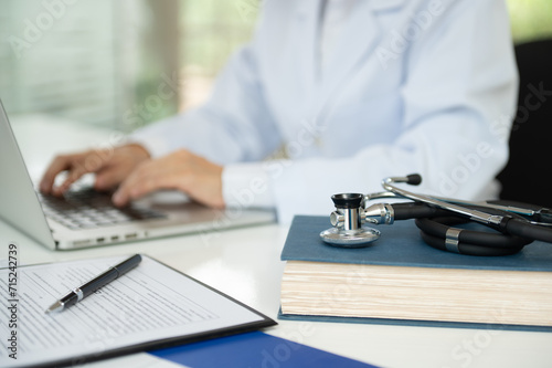 Bild auf Leinwand Stethoscope on medical textbook with Medical Writers use computer to typing information of clinical trial documents and medical information
