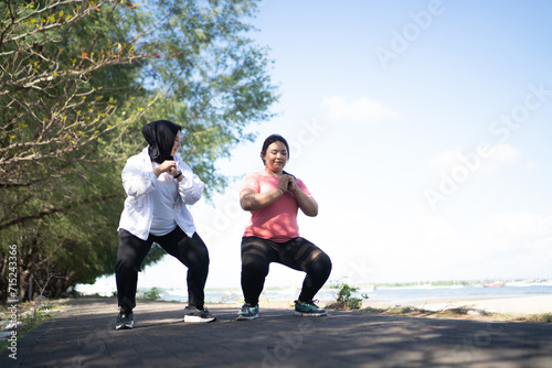 asian sporty women warming up together doing squat pose