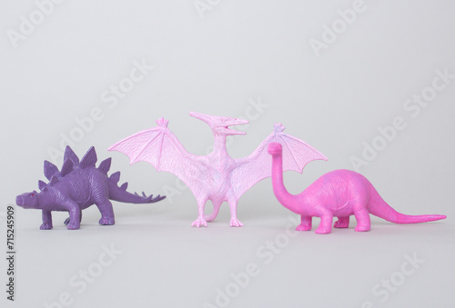 Fototapeta Naklejka Na Ścianę i Meble -  Tree small plastic dinosaur figurine on gray background, little plastic colorful statuettes