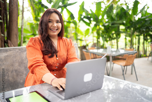 plus size woman working in outdoor cafe using laptop and tablet