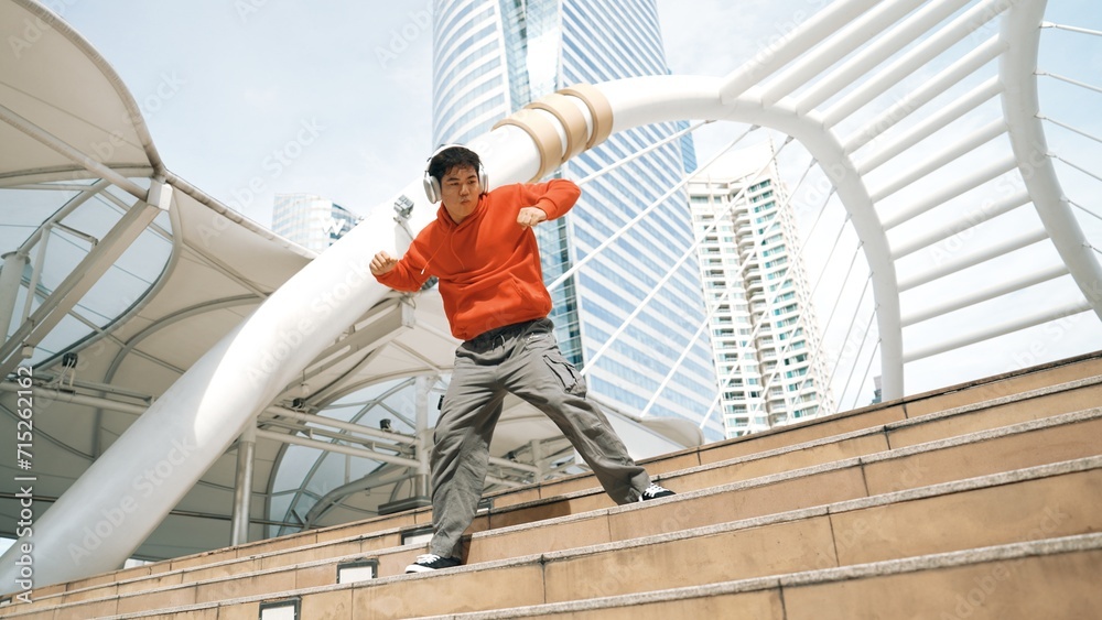 Asian hipster wearing headphone show footstep while jumping at city. Professional break dancer perform b-boy dancing performance at city. Break dance or street dance. Outdoor sport 2024. Sprightly.