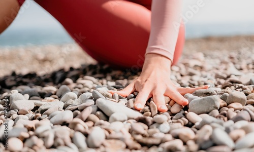 Middle aged well looking woman with black hair, fitness instructor in leggings and tops doing stretching and pilates on yoga mat near the sea. Female fitness yoga routine concept. Healthy lifestyle