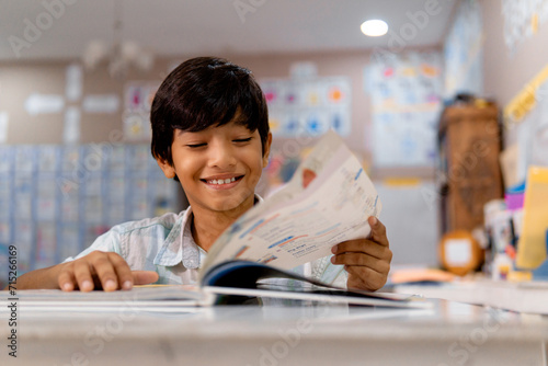 Portrait of elementary boy reading a book in a class. photo