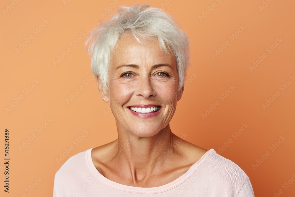 Portrait of a happy senior woman smiling at camera against orange background Portrait of a happy senior woman smiling at camera against orange background