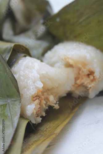 Indonesian food called lemper made from sticky rice and filled with chicken and wrapped in banana leaves on the table photo