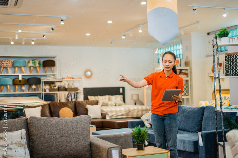 female store supervisor checks using a tablet while standing in a furniture store female store supervisor checks using a tablet while standing in a furniture store