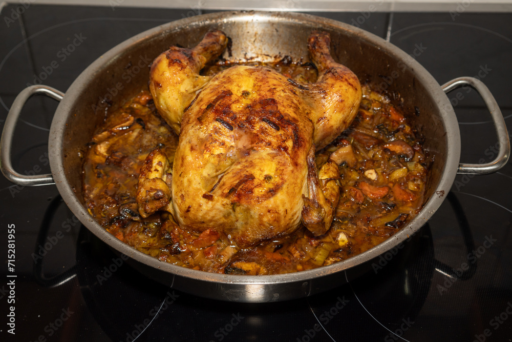 Whole chicken on a bed of vegetables fresh from the oven in a steel pan. Close-up Whole chicken on a bed of vegetables fresh from the oven in a steel pan. Close-up