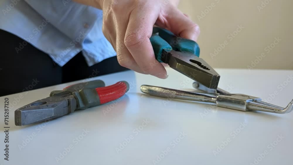 Woman grabbing pliers, variety of pliers on desktop Woman grabbing pliers, variety of pliers on desktop