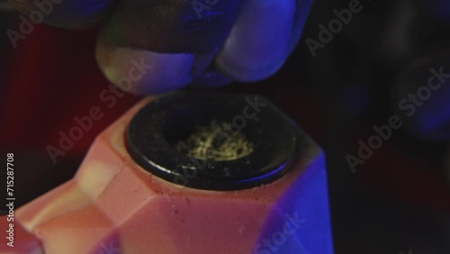 a black mans hand is breaking down marijuana bud to smoke it from a rubber pipe photo