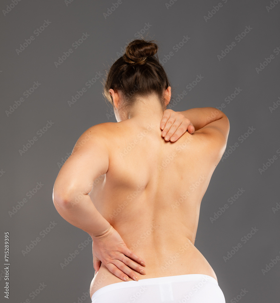 Young woman massaging back pain on gray background
Young woman massaging back pain on gray background