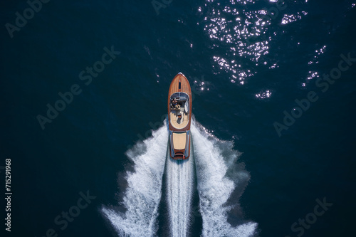 Classic Italian wooden boat fast moving aerial view. Top view of a wooden powerful motor boat. Luxurious wooden boat fast movement on dark water.