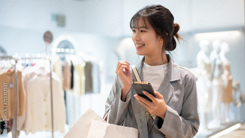 An attractive Asian woman with shopping bags is enjoying shopping in a shopping mall.