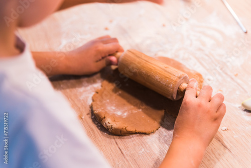 Close up hands kneading a dough on a wooden table.