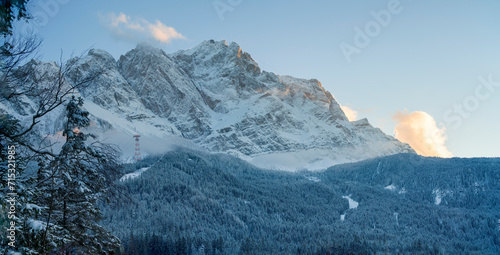 A bottom up view to the ice cold and with snow covered Zugspitze mountain chain and the surrounding forest nature landscape