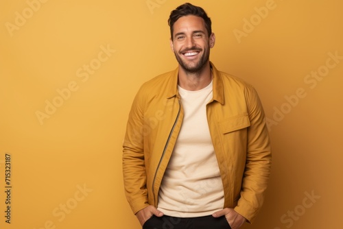 smiling handsome man in yellow jacket looking at camera isolated on yellow