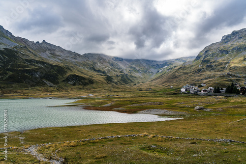 Reservoir lake in the Italian Alps near mountain pass Splügen with big mountain range and italian mountain village in the background