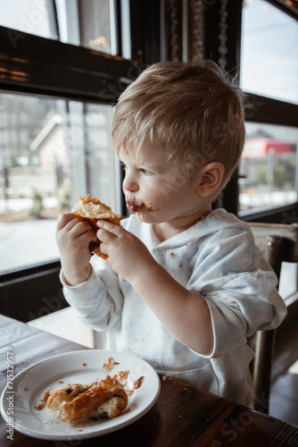 Toddler boy at a cafe enjoying chocolate croissant at a coffee shop