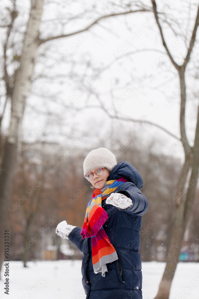 A girl plays with snowballs in a winter park