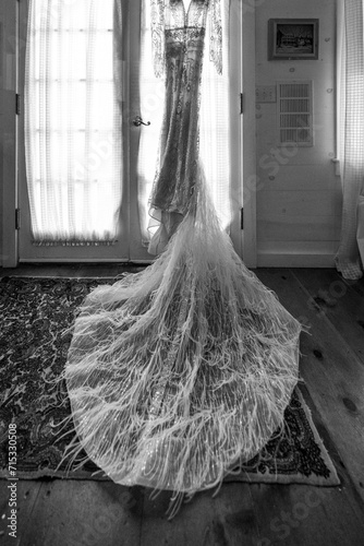 Black and white image of wedding dress hanging from a door photo