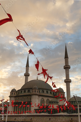 Taksim Camii mosque and turkish flags under a sunset sky
