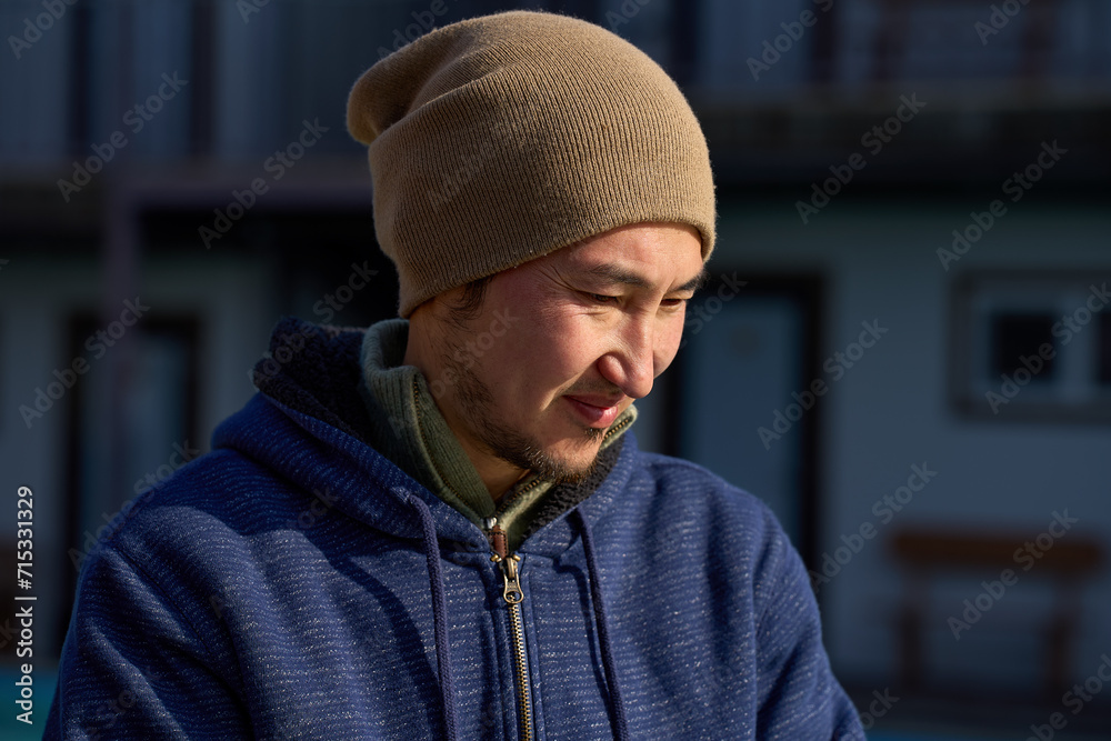 A man in warm clothes squints from the bright sun A man in warm clothes squints from the bright sun