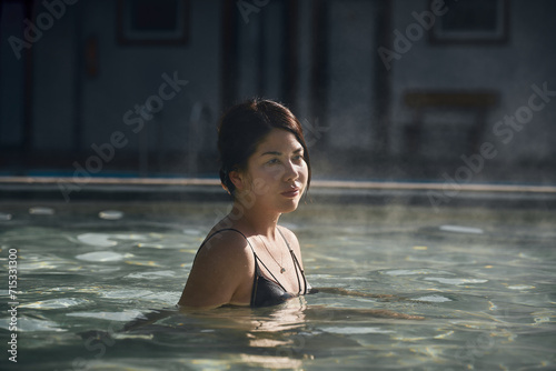 A young Asian girl, 25-30 years old, bathes in a hot springs poo photo