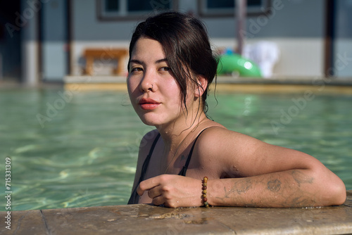 Young attractive Asian woman bathes in hot springs, leaning on t photo