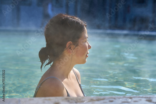 A young girl is relaxing at a resort, bathing in hot springs, st © Cavan