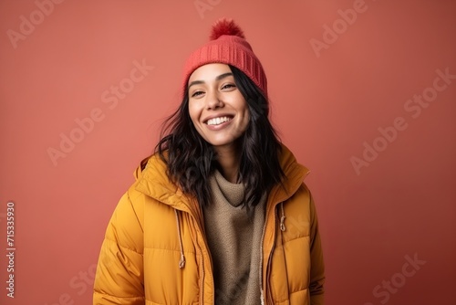 Portrait of a smiling young woman in winter clothes on a red background © Inigo