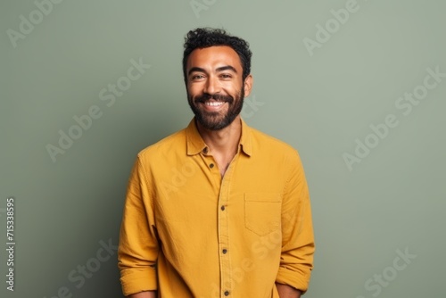 Portrait of a handsome Indian man smiling while standing against green background © Inigo