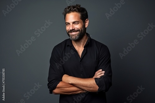Handsome middle age man with beard and mustache in black shirt over grey background.