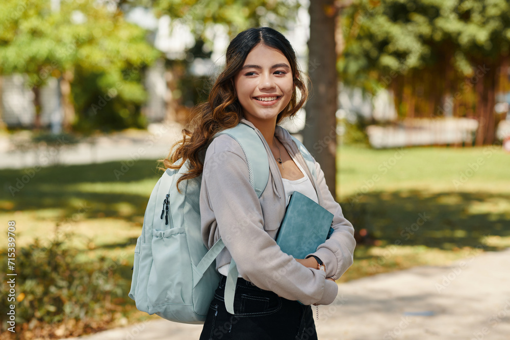 Portrait of smiling high school student with backpack and planner standing on school campus Portrait of smiling high school student with backpack and planner standing on school campus