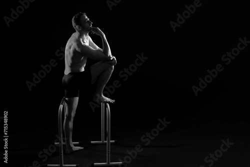 Male gymnast performing handstand on parallel bars, studio shot © Ivan Zelenin