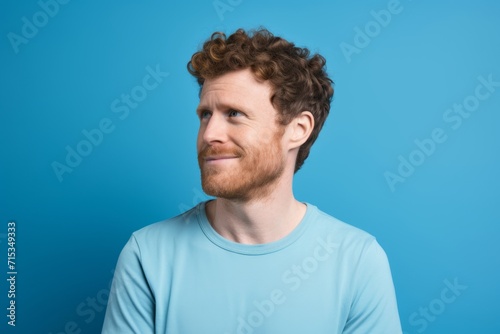 Portrait of a handsome young redhead man on blue background. © Loli