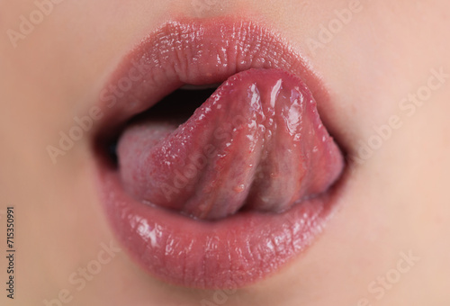 Sexy lips. Plump glossy lip. Tongue out. Closeup of female sticking tongue out and licking lips. Macro tongue lick lips. Close up of woman mouth with tongue. Sexy tongues. Sensual lips lick. photo