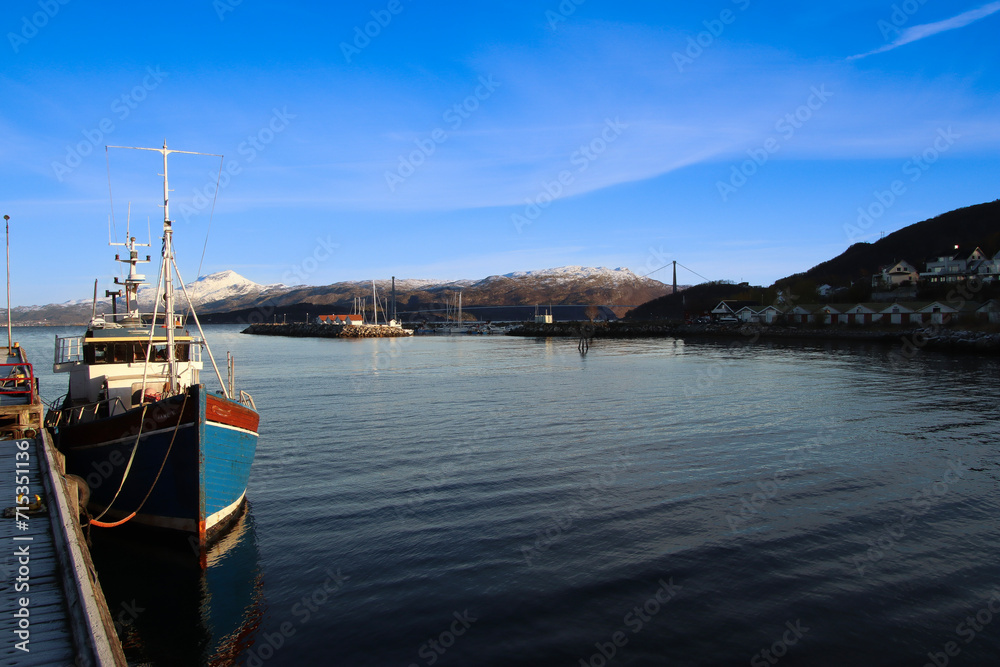 Fototapeta premium small harbor with a fishing boat in Norway with mountains in the background