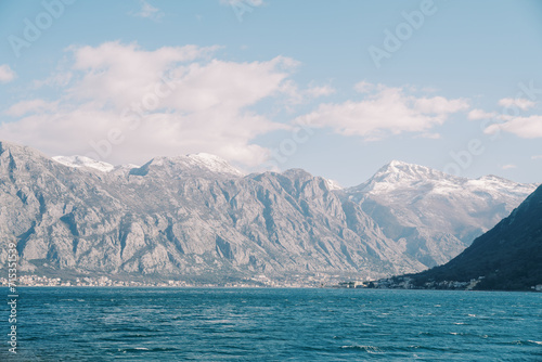 Turquoise sea at the foot of a high mountain range with snow-capped peaks. Montenegro