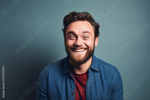 Portrait of a young man laughing over grey background. Looking at camera.