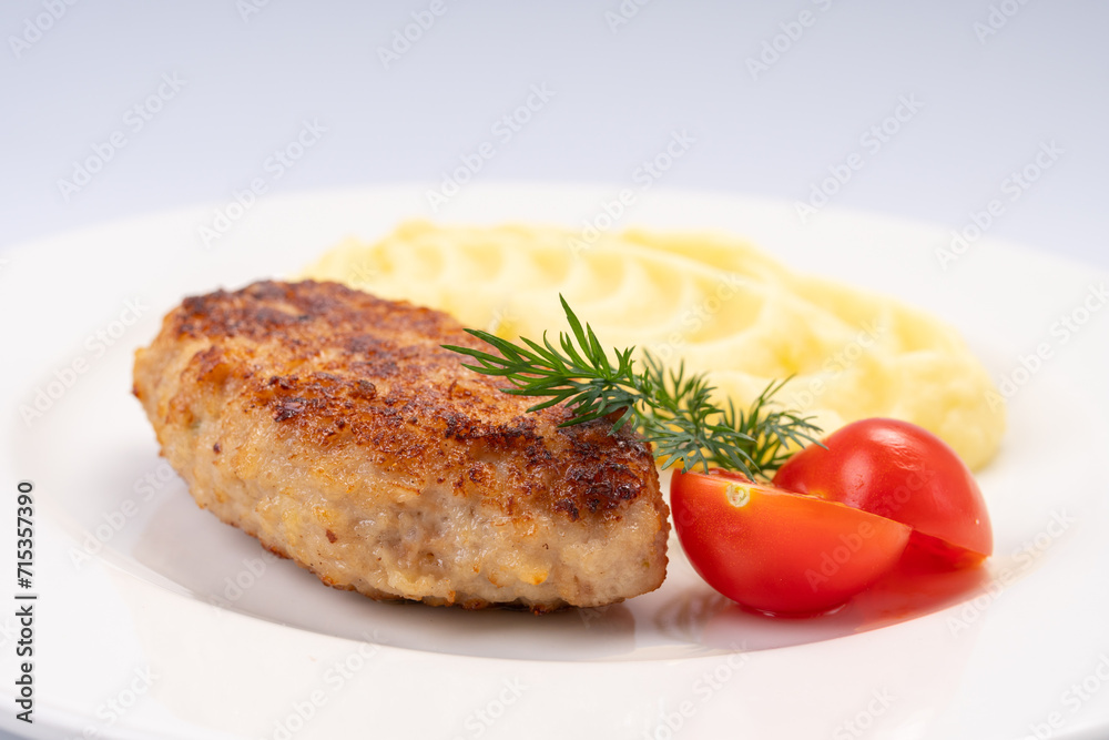 Dinner. Fried cutlet in mashed potatoes on a white plate and a white background