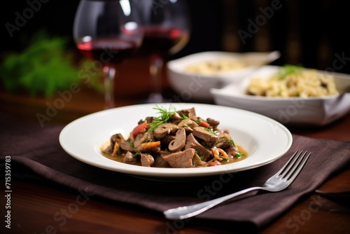 beef stroganoff ready for serving, with a glass of red wine beside it