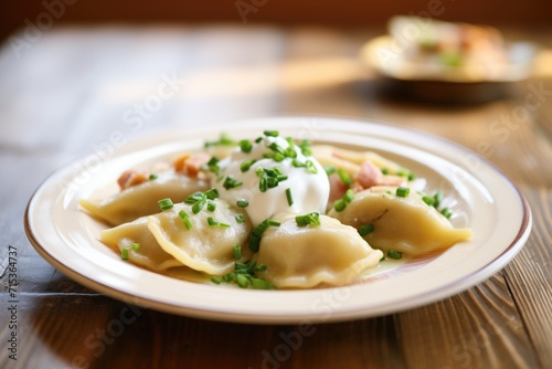 plate of boiled polish pierogi with sour cream and chives