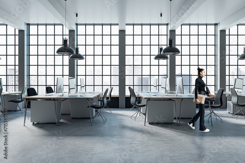 Pretty blurry woman walking in modern coworking office interior with large panoramic windows with city view, lamps, concrete flooring and other objects. photo