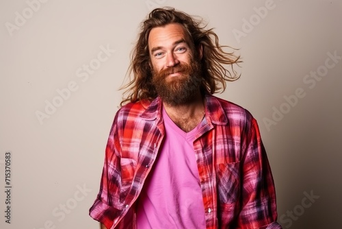 Handsome long-haired man with a long beard and mustache in a pink shirt on a gray background