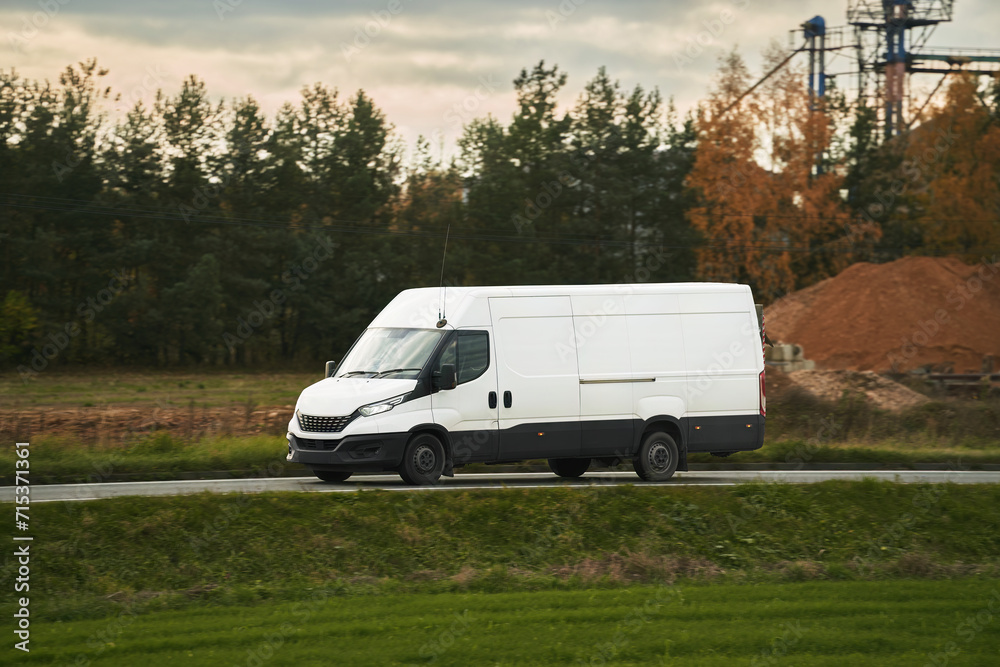 A mockup of a white van with an empty wrap for you to customize. A commercial vehicle for your delivery and transport service. Isolated small white truck on the road.