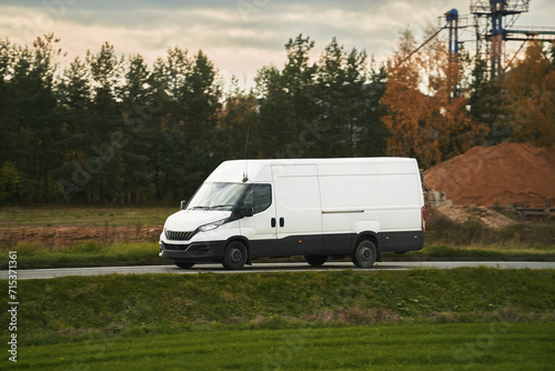 A mockup of a white van with an empty wrap for you to customize. A commercial vehicle for your delivery and transport service. Isolated small white truck on the road.