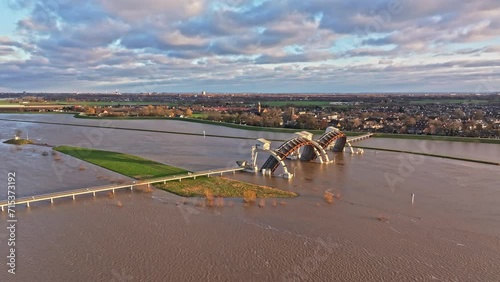 Aerial orbit drone shot to the right at the weir of Driel during high water levels with the doors open and with the town of Driel in the background photo