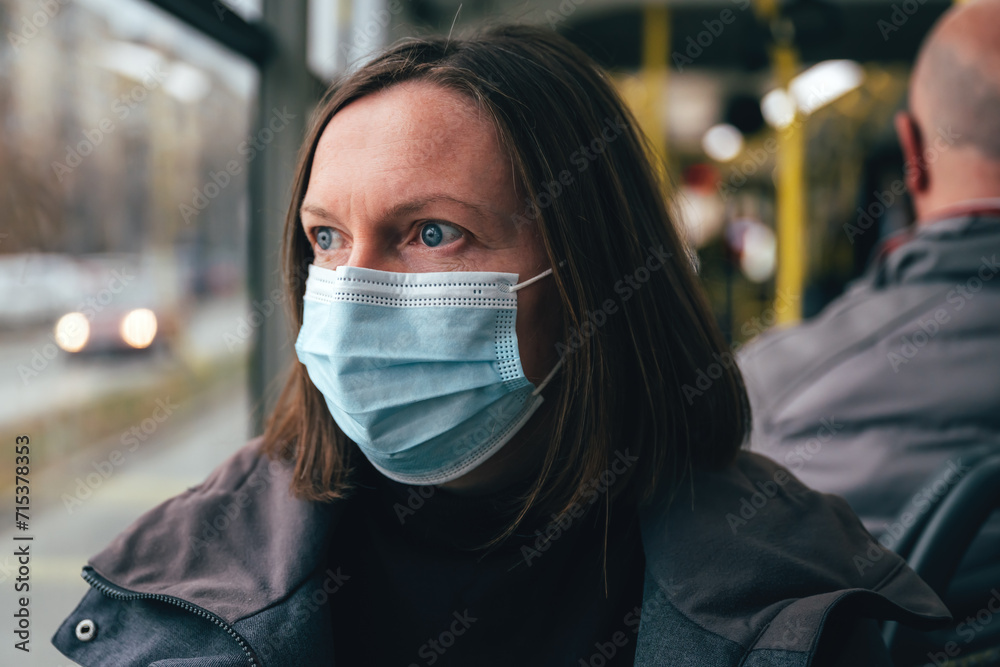 Woman with protective face mask riding public transportation bus in winter