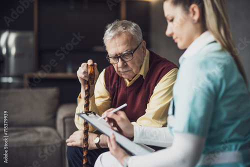 Home doctor is visiting senior man to check his health. Professional caregiver is assisting old man at his home. photo